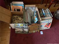 Seven boxes containing multiple vinyl records, showing a variety of album covers, mainly upright for display.