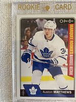 Front of 2016-17 O-Pee-Chee #694 Auston Matthews rookie hockey card in magnetic clear holder labeled 'ROOKIE CARD' with gold text.