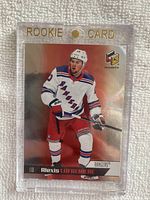 Front of 2020-21 Upper Deck HoloGrFx Alexis Lafreniere rookie card in clear magnetic holder showing player in Rangers uniform with holographic effects and Rookie Card header.