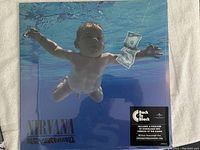 Front cover of Nirvana Nevermind vinyl showing the iconic underwater baby holding money, sealed with Back To Black sticker.
