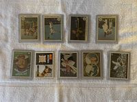 Top view of ten baseball cards laid out in two rows on white fabric background showing front faces.