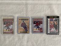 Four hockey rookie cards including Cole Caufield cards and a Young Stars checklist card with Trevor Zegras.