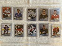 Photo of 10 hockey rookie cards arranged in two rows of five, individually sleeved in clear holders, showing players in various NHL team uniforms.