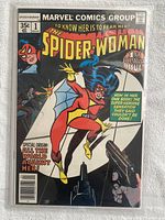 Full front cover of Spider-Woman #1 comic book showing the character in red and yellow costume with gun sights aimed at her, text highlights '1st spectacular issue' and pricing details.