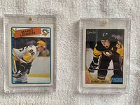 Two Mario Lemieux hockey cards side by side in clear magnetic holders, placed on a textured neutral background.