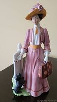 Porcelain figurine showing a woman in pink with a suitcase and a Scottie dog beside her