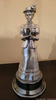 Metal figurine of a lady in classic attire on a round base