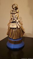 Photo of bronze-colored award statue of a woman in period costume on a blue base with plaque