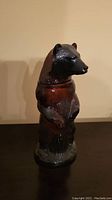 Full view of a standing Kodiak bear ceramic figurine on a flat surface against a beige background.