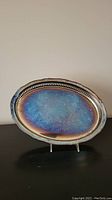 Photo of an oval silver plated tray with visible tarnish, showing discoloration and beaded edge detailing.