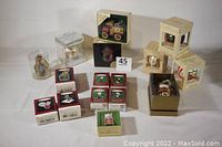 Photo showing 16 Hallmark Keepsake Christmas tree ornaments all in original boxes arranged on a surface. Various ornament themes and box designs are visible.