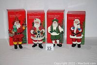 Four Possible Dreams Clothtique Santa figurines with original red boxes in background.