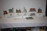 All six Heritage Village Collection houses from the New England Village Series displayed on their boxes with a yardstick for size reference, showing variation in size and design.