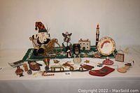 Wide view of assorted country Christmas ornaments and decorations arranged on a white surface over a green table runner