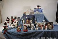Overview of the lot showing various snowman figurines, stocking holders, and the embroidered fabric.