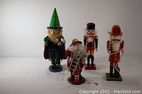 Front view of four nutcrackers on white background including Wizard of Oz, traditional soldier, and two fireman-santas.