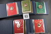 Five cloth-covered folders each containing four holiday greeting cards with bronze medallions, showing first card of each year 1978-1982.