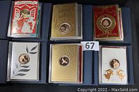 Six holiday greeting cards each with a bronze medallion displayed in cloth-covered folders, representing the years 1988 to 1993 with the first greeting card design for each year.