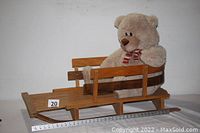 Wooden sled with teddy bear seated on it, showing full length and scale with measuring tape.