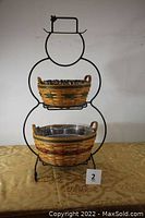 Front view of the wrought iron snowman stand with two baskets attached, showing the overall shape and size.