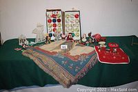 Overview of lot showing two open boxes with vintage Christmas balls, multiple angel figurines, and a shawl spread on table