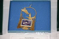 Photo of 1994 holiday collectible ornament in original box, gold-toned metal with duck design and stamp replica