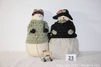 Two Victorian-style snowmen, one pulling a small pull toy sheep on wheels, shown together