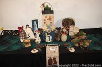 Photo of full lot showcasing assorted snowmen figurines, large pinecones, and a wooden light-up snowman box, all arranged on a plaid cloth.