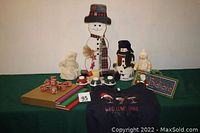 Photo showing entire lot: wooden snowman, small snowman figurines, three-volume books, sweatshirt, snowman candles, and other decorations.