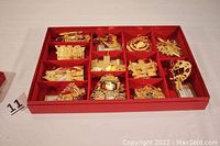Photo showing the set of 12 brass Christmas Seal ornaments arranged neatly in a red compartmentalized box, showcasing shiny brass finish and detailed designs.