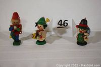 Three colorful mini-Steinbach wooden figurines including a nutcracker, front view showing details and facial features