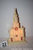 Front view of vintage plastic cathedral electric light showing detailed facade, stained-glass style windows lit internally.