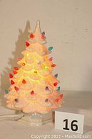 Front view of the illuminated white ceramic Christmas tree with colorful bulbs lit up.