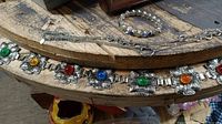 Photo showing silver tone belt with large flower-shaped links each holding colored stones, along with chain necklace and bracelet.