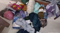 Overview of assorted yarn skeins in various colors and textures spread on floor.