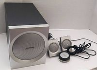 Front angle showing the subwoofer and the two satellite speakers alongside the control pod with connected cables.