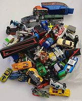 Top view of the pile showing a wide variety of die cast cars and vehicles with mixed colors and models.