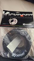 Front view of the new KickPort bass drum acoustics maximizer sealed in plastic packaging showing the product and branding.