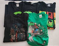 Lot of 5 DC Comics themed t-shirts folded and arranged showing different designs and colors