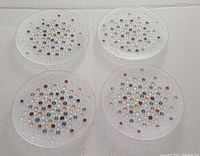 Four clear glass Dansk Confetti salad plates arranged on a white background showing colorful dot pattern