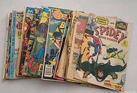 Stack of vintage comic books showing colorful front covers including Spidey Super Stories, Batman, and more.