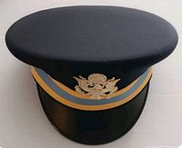 Front view of black US Army officer cap with flat top, gold and blue band, and gold eagle emblem embroidered on front.