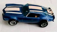 Side angle of the blue AFX Camaro HO scale slot car showing white racing stripes on hood, roof, and rear with black wheels and detailed body.