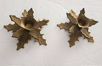 Two vintage brass poinsettia candle holders on white background, angled top down view showing embossed leaf details and central candle cup.