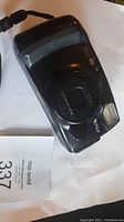 Front view of a black Fuji DL-1000 Zoom film camera showing lens and built-in flash.