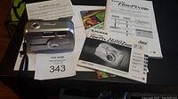 Overall lot including FujiFilm FinePix 2600 Zoom digital camera, manuals, disc, and memory card on table surface.