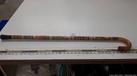 Full length of the cane placed alongside a measuring tape showing approximately 37 inches length
