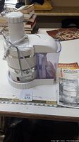 White Jack LaLanne Power Juicer model JLS-88 with clear pulp catcher and user manual on table.