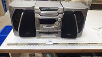 Panasonic mini stereo system with two speakers placed on table with measuring scale.