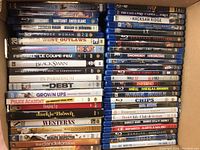 Top view of stacked DVDs and Blu-rays showing titles and spines in a box.